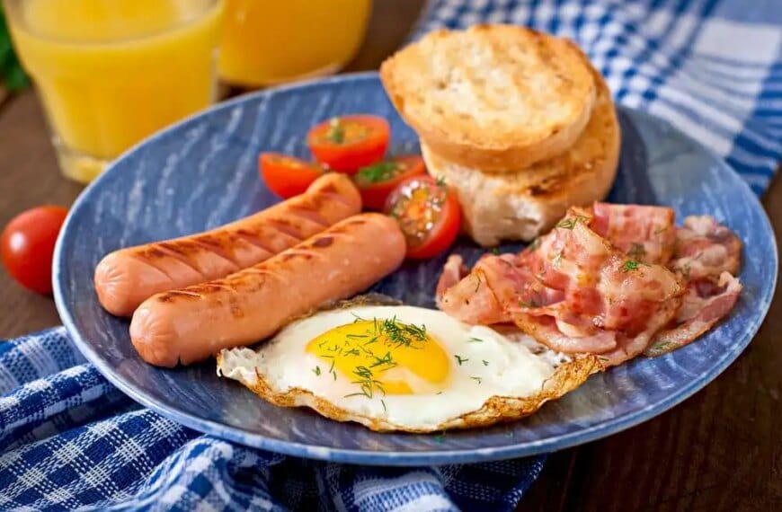 A classic breakfast plate with eggs, bacon, sausages, toast, and tomatoes.